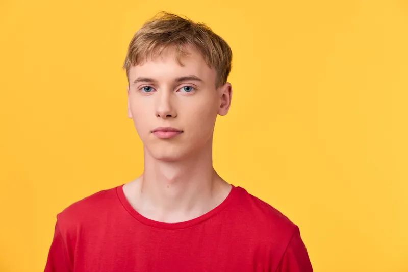 Young man, red shirt, yellow background, minimalist, studio lighting, casual fashion, calm expression, male model, front view with clean background and bright mood showcasing simple style