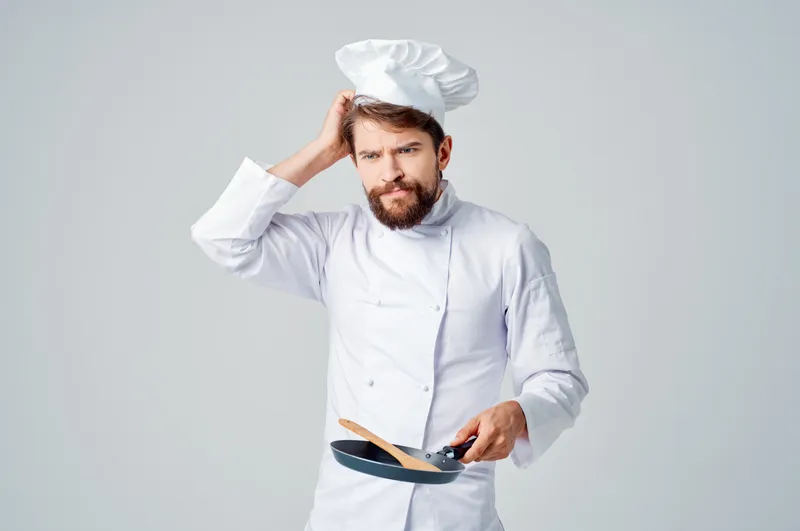 Профессиональный повар жарит еду на сковороде, работая на кухне