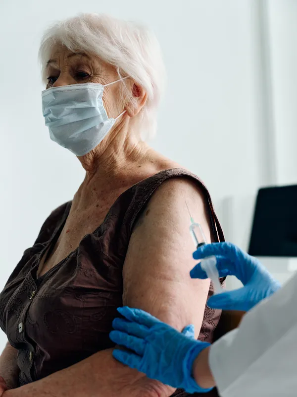 Пожилая женщина-пациентка получает паспорт вакцинации от COVID-19 в больнице