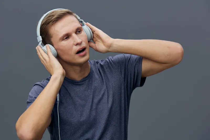 young caucasian man wearing headphones listening music enjoy sound closeup gray background technology concept digital detox headphones audio lifestyle