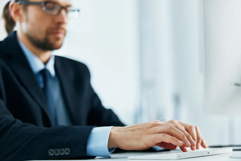 Руки на клавиатуре на рабочем столе, работа за компьютером в офисе