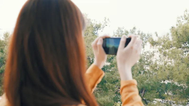 Женщина с телефоном в руках фотографирует природу на открытом воздухе, снимая панораму