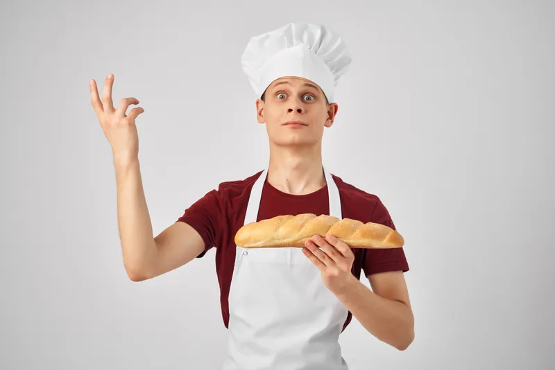 Весёлый пекарь с буханкой хлеба в руках готовит выпечку