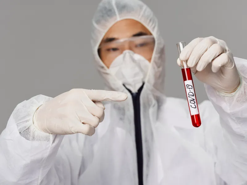 Мужчина-лаборант указывает пальцем на тесты на COVID-19