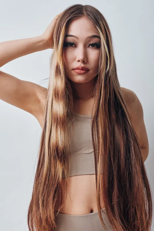 Young woman with very long straight hair posing in casual top with neutral facial expression on plain background. Beauty, hairstyle, fashion and portrait concept for style and youth.