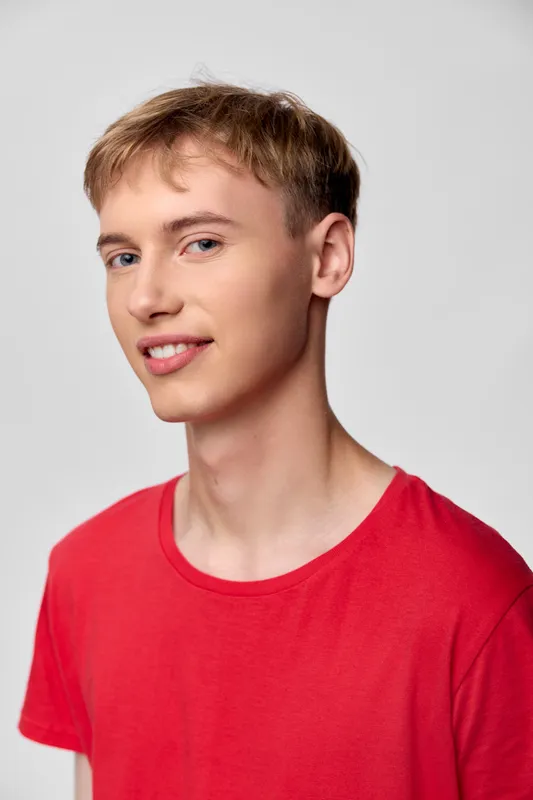 Young man wearing a red t shirt in a casual studio setting, relaxed smile, clean background, minimal styling, suitable for lifestyle or fashion advertising and editorial use