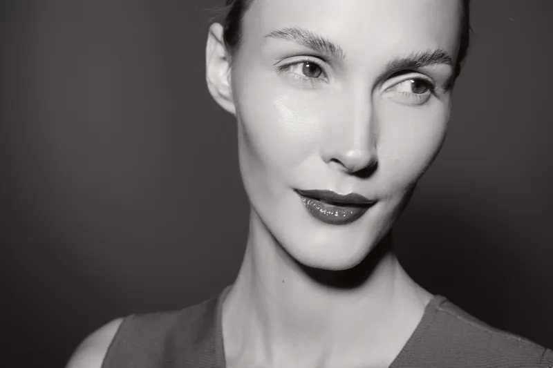 Closeup portrait of a white woman with fair skin and slicked hair looking to the side in black and white.