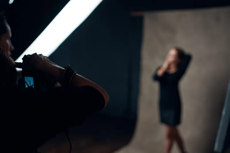 Женщина позирует фотографу в профессиональной студии