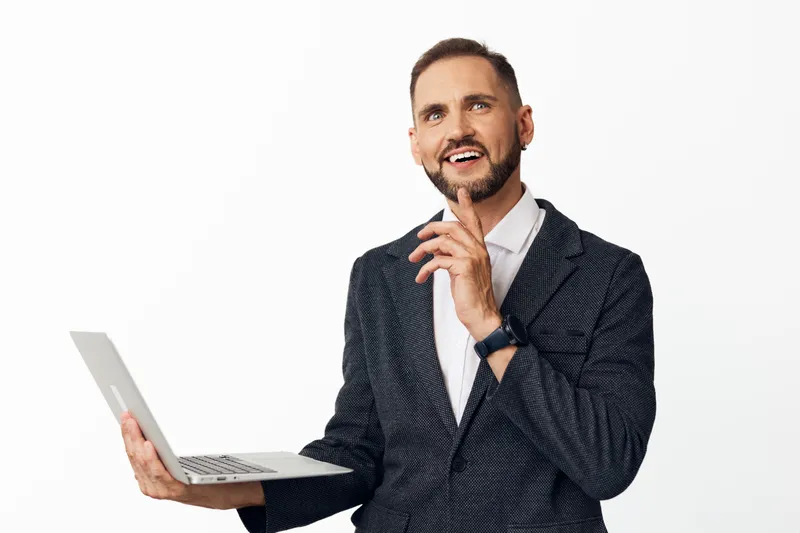 A professional businessman stands against an isolated colorful backdrop, holding a laptop, smiling with confidence, and conveying emotion, focus, and readiness for new challenges.