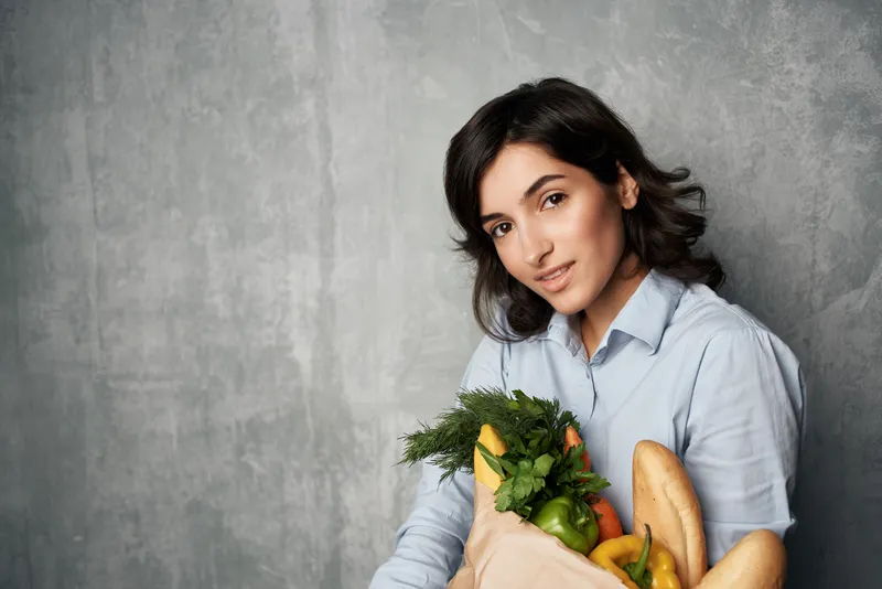 Женщина в осенних рубашках с пакетом продуктов из супермаркета