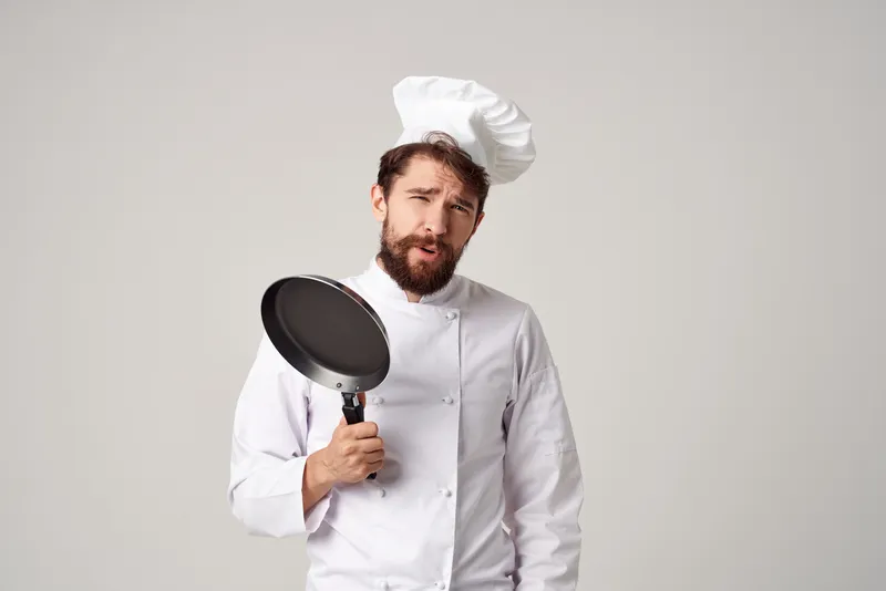 Бородатый мужчина-шеф-повар с кухонной утварью, работа в кулинарной индустрии