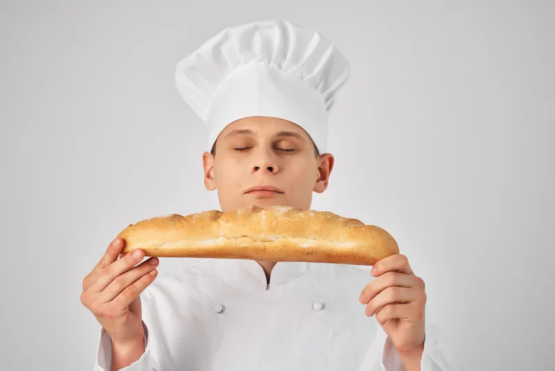 Повар-мужчина держит в руках багет — свежий продукт, профессиональная работа