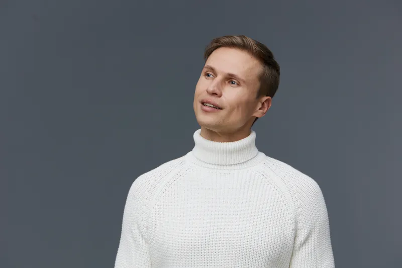thoughtful man wearing white turtleneck sweater look up ponder on gray background digital detox mental health concept