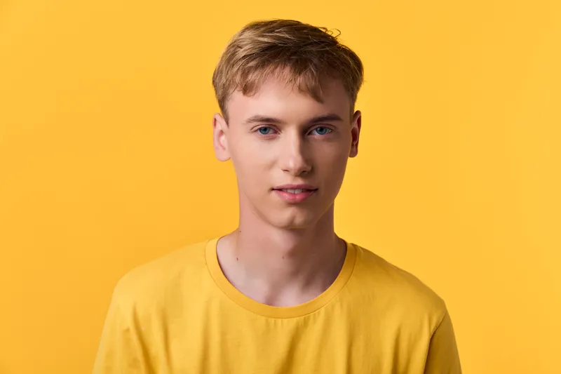 Young man in a yellow tee against a bright yellow backdrop, casual lifestyle image suitable for fashion and youth concepts, clean lighting and friendly mood for stock use