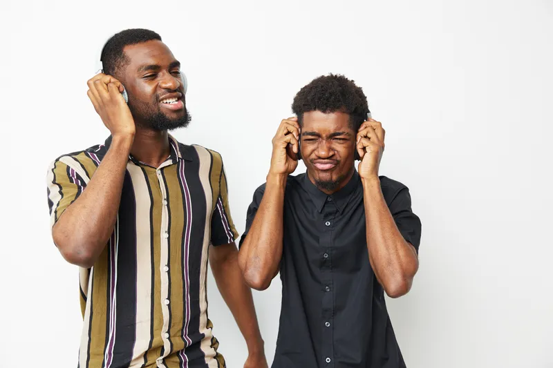 Joyful African American men enjoying music together with headphones, expressing happiness in a fun, vibrant atmosphere. Perfect for lifestyle and music themes.