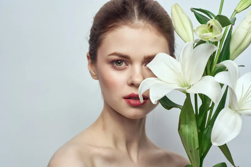 Женщина с белыми цветами на сером фоне, портрет крупным планом, макияж, образ