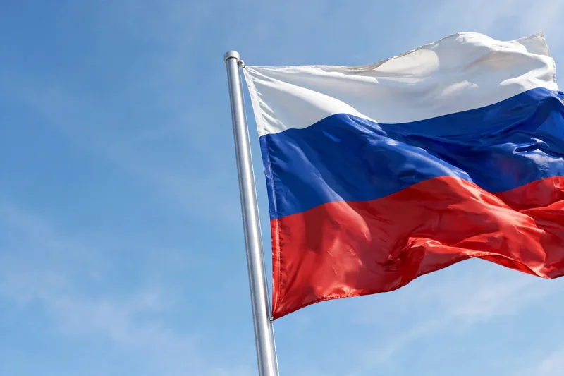 Российский флаг развевается на фоне ясного синего неба