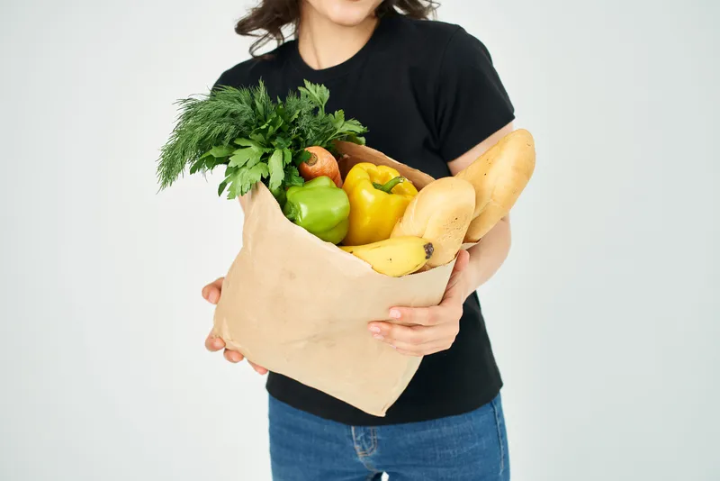 Пакет с продуктами, овощи из супермаркета на светлом фоне
