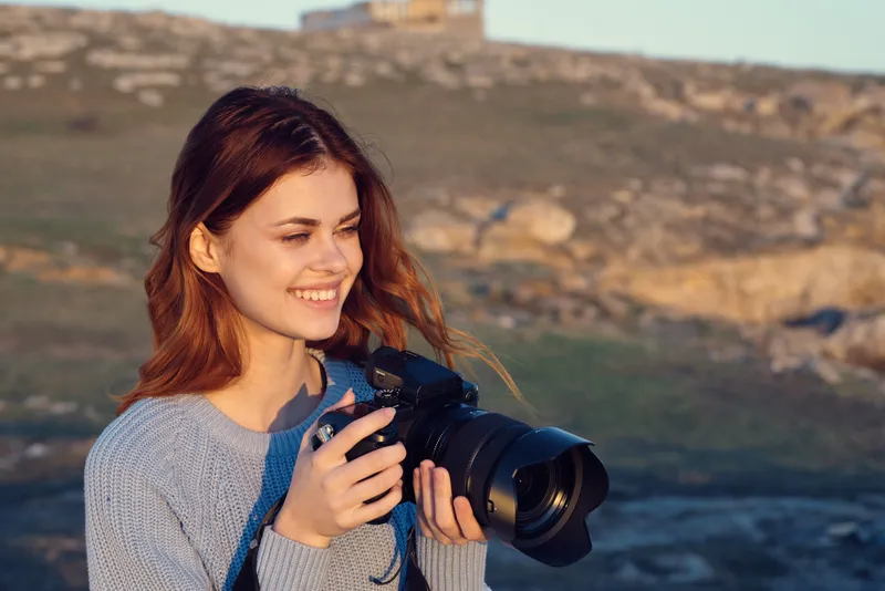 Жизнерадостная женщина-фотограф работает на открытом воздухе, среди природы, сочетая работу и образ жизни