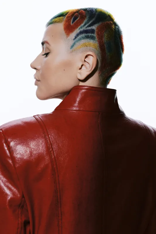 Woman with colorful short hair wearing red leather jacket, side profile portrait with closed eyes, modern artistic hairstyle, clean white background, fashion style.