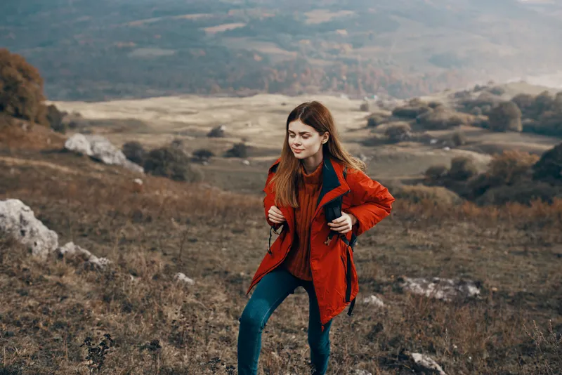 Женщина в куртке с рюкзаком в горах, степной пейзаж, осень, теплая одежда, модель