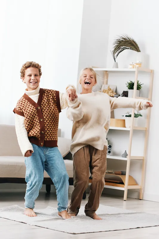 Authentic scene of children at play in a bright home, capturing school themed lifestyle through joyful movement, candid expressions, and everyday attire.