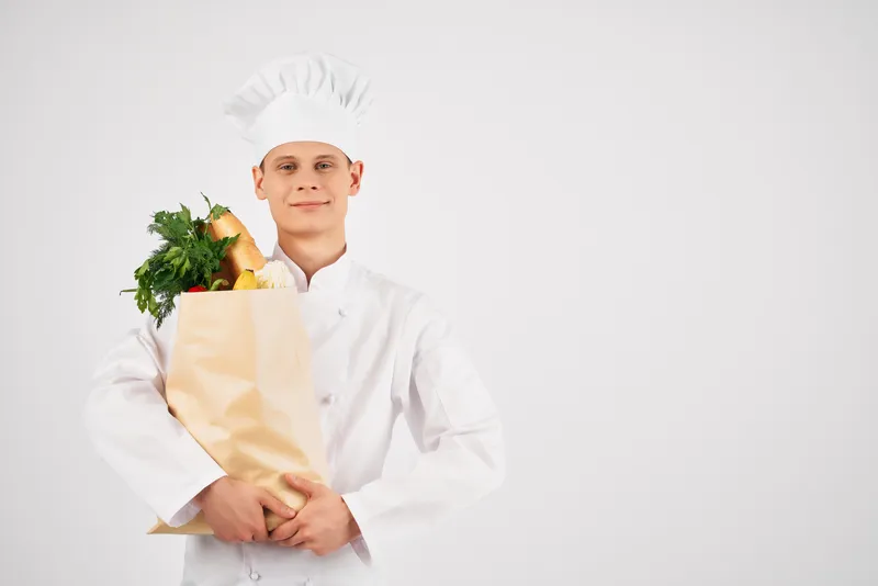 Мужчина в форме шеф-повара с пакетом продуктов для доставки