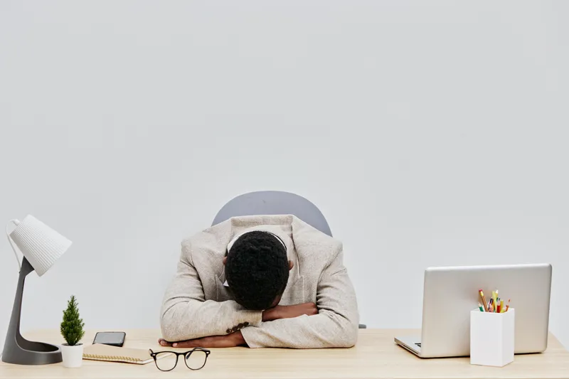 Businesswoman overwhelmed exhausted stressed in office sitting at desk with head down, workplace chaos, cluttered workspace, feeling burnout, fatigue, work pressure concept, modern business environmen