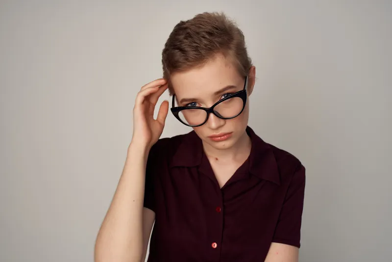 Женщина с короткой стрижкой позирует на светлом фоне
