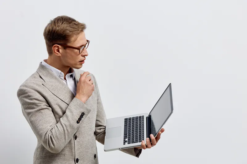 serious caucasian man holding laptop looking screen wearing striped beige blazer glasses isolated on gray background digital nomad working concept