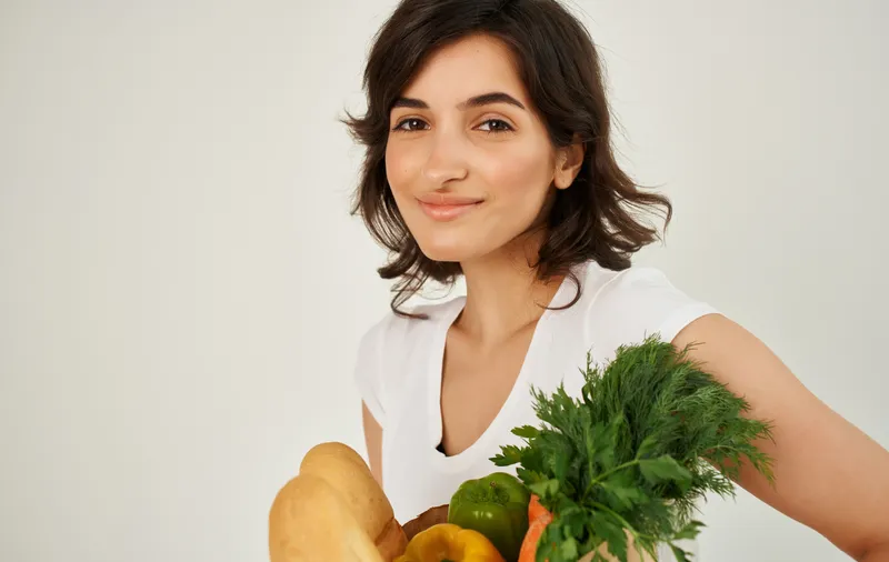 Весёлая женщина с пакетом здоровой еды, свежие продукты