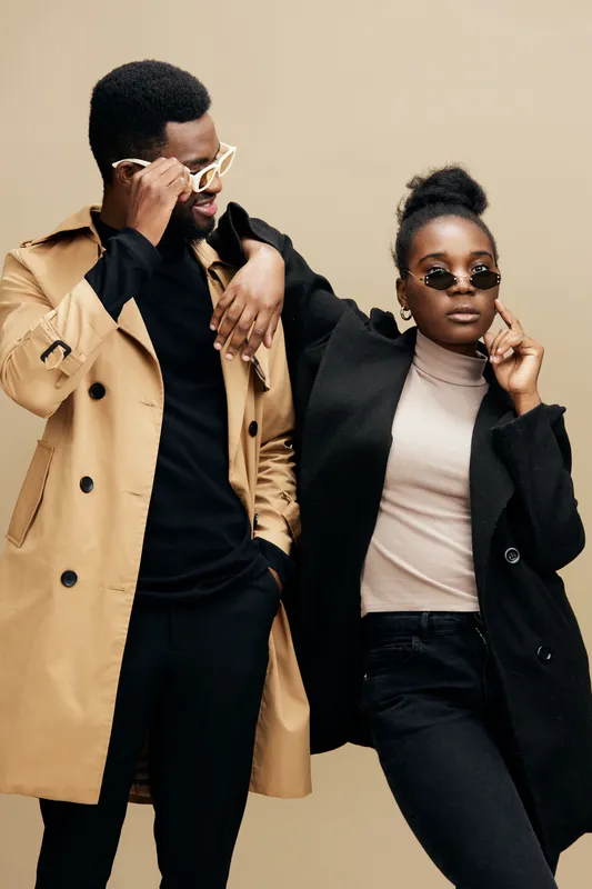 Stylish couple in contemporary fashion poses against a neutral background, showcasing modern eyewear trends and seasonal style