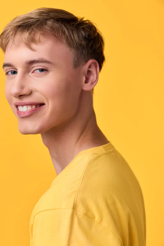 Smiling man in a casual yellow shirt stands against a vivid yellow backdrop, exuding cheerful energy and approachable style, ideal for lifestyle, fashion, or positivity campaigns.