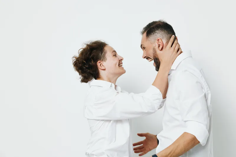 A professional man in a business setting shares a smile with a colleague in a studio, isolated on a bright colored background, conveying teamwork, leadership, and positive emotion.