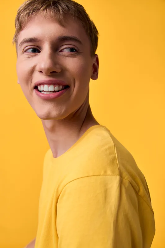 Smile, man, yellow, studio, casual, joyful features accompany a smiling man in a yellow shirt in a studio with bright sunlight for lifestyle branding and a friendly, energetic vibe