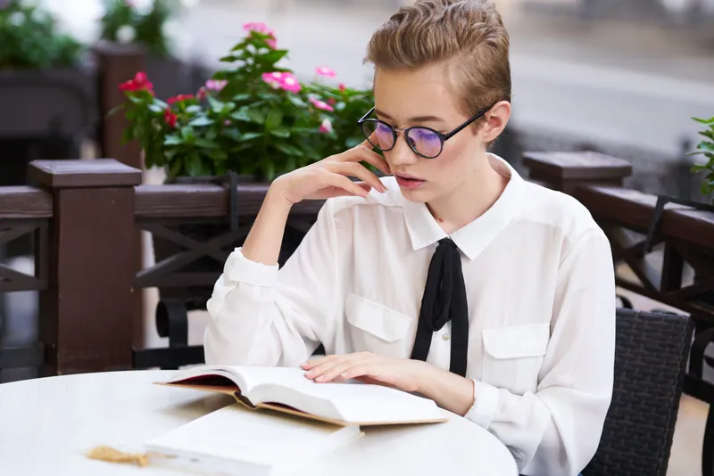Студент с книгой в руках на открытом воздухе отдыхает, веселится, гуляет по городу и общается