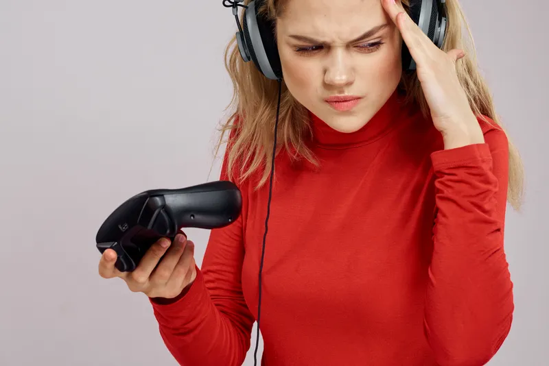 Женщина в наушниках держит в руках джойстик и играет в игры