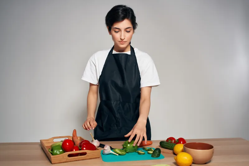 Веселая женщина на кухне, домохозяйка, готовит овощи