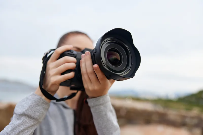 Young woman photography enthusiast capturing the beauty of nature with a digital camera, showcasing a passion for outdoor photography in a serene environment