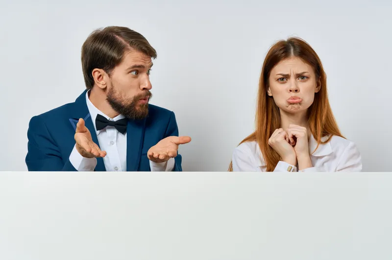 Мужчина и женщина рекламируют презентацию с белым баннером в студии, оставляя место для копирайтинга