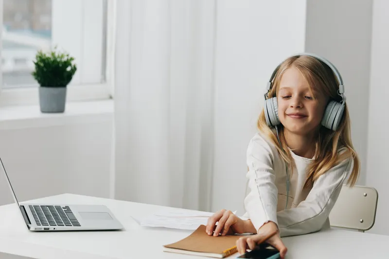 Улыбающаяся девушка-подросток использует ноутбук для онлайн-обучения дома, современные технологии и образование в киберпространстве