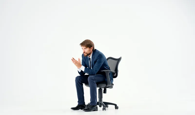 Бизнесмен сидит в кресле в офисе, работает на светлом фоне