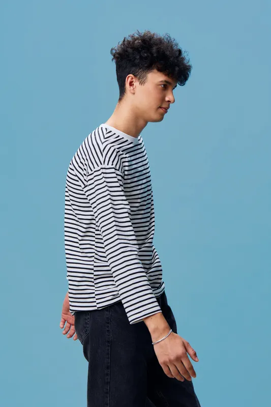 young man in striped shirt walking against blue background, casual hairstyle, side profile, modern fashion, relaxed mood, studio portrait