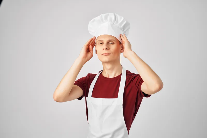 Мужчина в фартуках на кухне, профессиональный светлый фон, повар