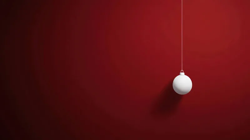 Одинокое белое украшение, подвешенное на тонкой нити на фоне глубокого красного цвета