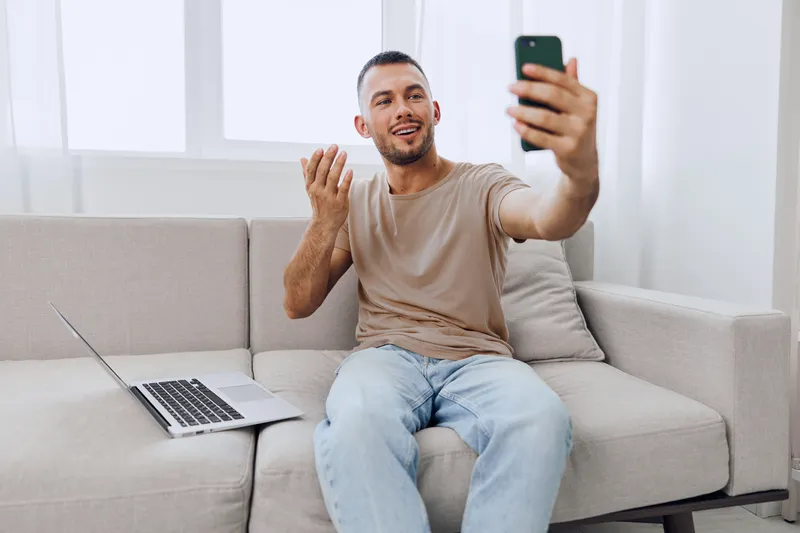 Man engaging in a heartfelt video call, showcasing emotional vulnerability and connection in a cozy home environment, illustrating the culture of therapy and mental health awareness.