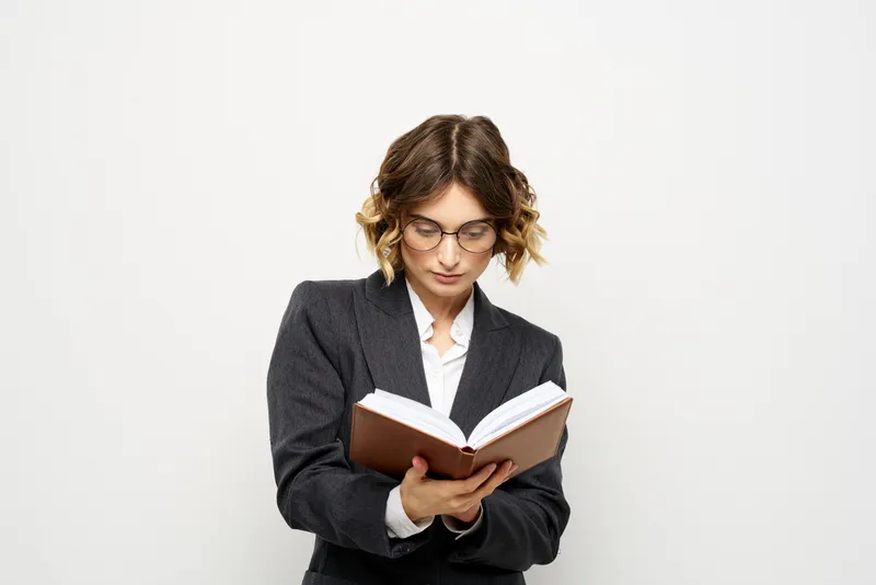 Женщина за работой с книгой в руке на светлом фоне
