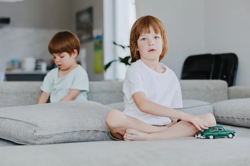 Thoughtful boy playing with a toy car in a modern living room, showcasing a calm and cozy atmosphere with soft lighting and stylish decor.