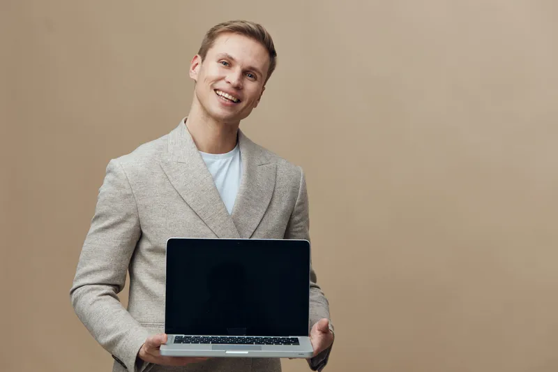 smiling happy young caucasian man hold laptop computer digital nomad casual beige background technology concept