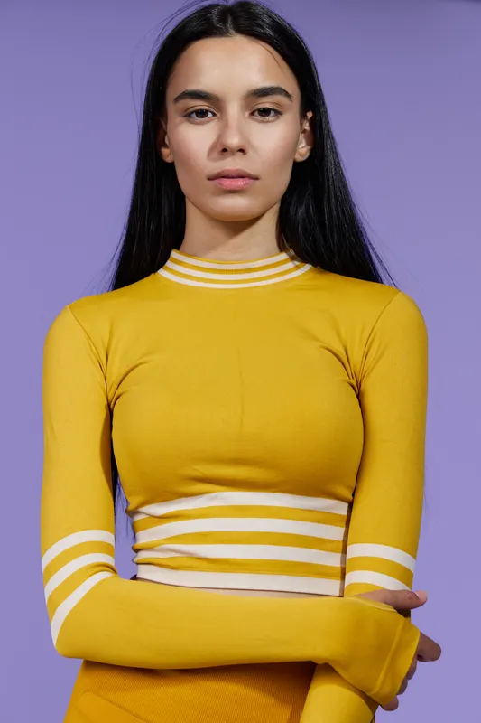 Sport fitness woman with determined expression wearing yellow athletic outfit against purple background, showcasing strength and focus for healthy lifestyle motivation.
